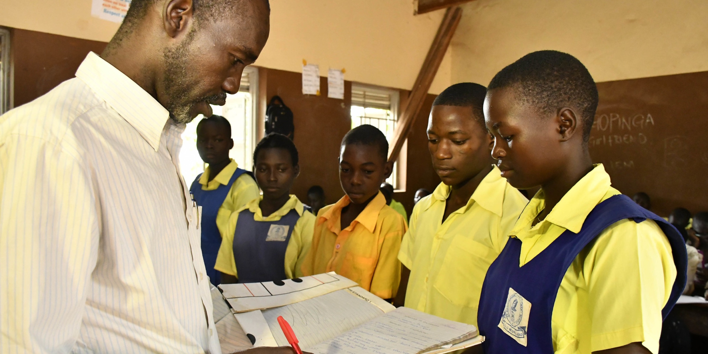 Teacher Adam Gabriel checks the work of his students Moses Justin, Daniel Adam and Salawa Emmanuel during a history lesson at St.Bakhita primary school. Credit: GPE/Jok Solomon